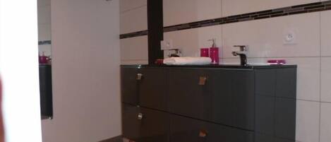 A bathroom with a dark vanity, white tiled walls, and a red rug.
