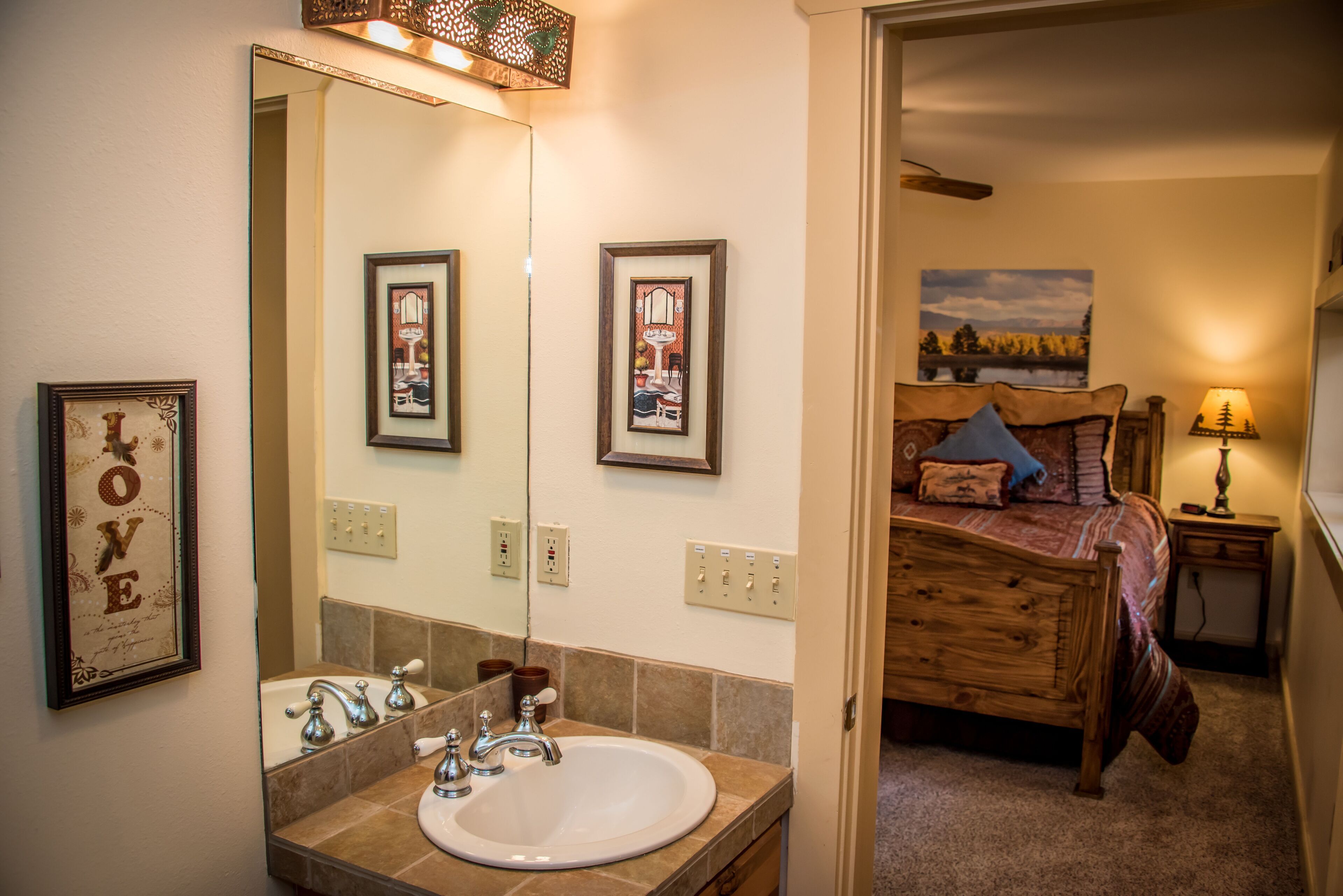 A bathroom with a sink, mirror, and framed pictures on the wall.