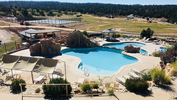 A large outdoor swimming pool with multiple sections, surrounded by lounge chairs and a covered seating area.