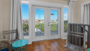 A balcony with a wooden floor, white curtains, and a view of a residential area. - Pool, 3 Mins to the Beach, Hidden Oasis in BMB + Free Attraction Tickets! (Santa Rosa Beach)