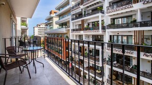 Un immeuble résidentiel à plusieurs étages, doté de balcons, d’un espace extérieur aménagé et de plantes en pot.