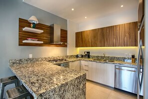 A modern kitchen with granite countertops, stainless steel appliances, wooden cabinetry, and a built-in oven.