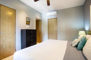 Une chambre à coucher comprenant un lit, une commode, un appareil de climatisation et un ventilateur de plafond.