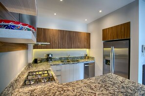 Une cuisine moderne équipée d’une cuisinière à gaz, d’appareils électroménagers en acier inoxydable et de meubles de rangement en bois.