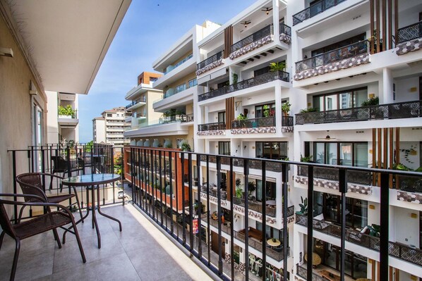 A multi-story residential building with balconies, outdoor seating, and potted plants.