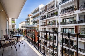 A multi-story residential building with balconies, outdoor seating, and potted plants.