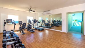 Une salle de sport équipée de tapis de course, de vélos elliptiques et d’haltères.