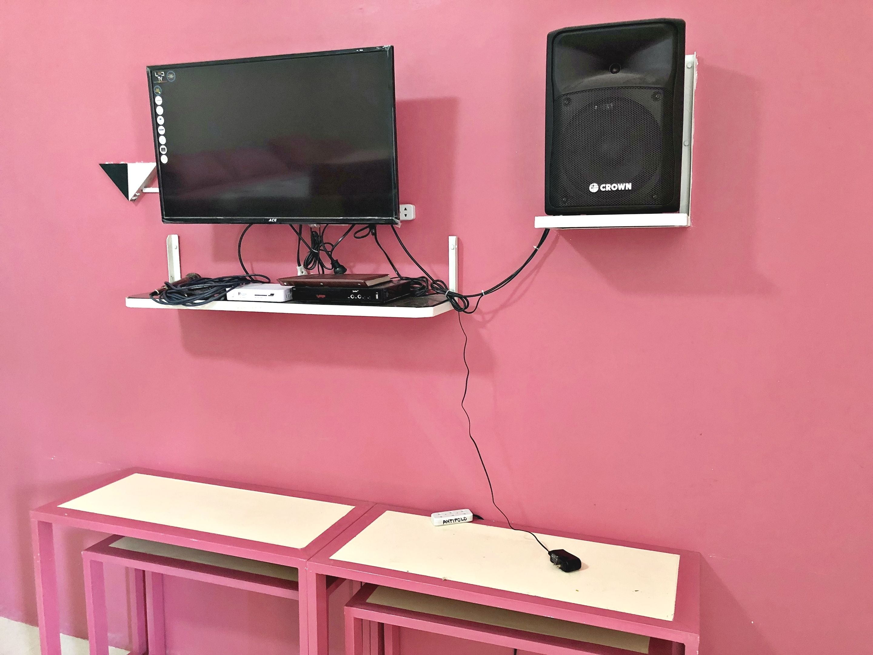 Una pared rosa con una computadora que incluye un monitor, un altavoz y un escritorio.