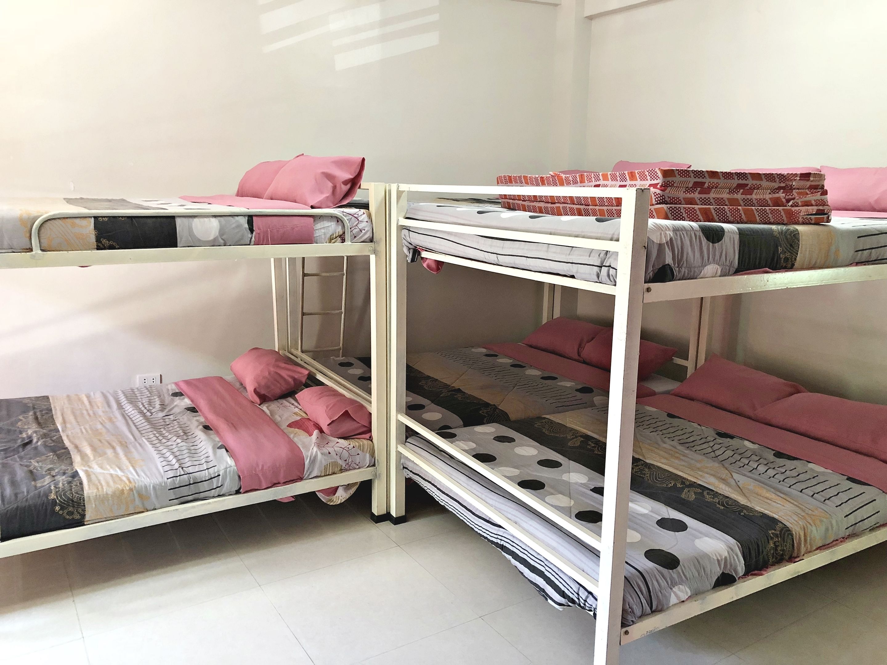 A bunk bed room with three levels, each with a mattress and pillows.