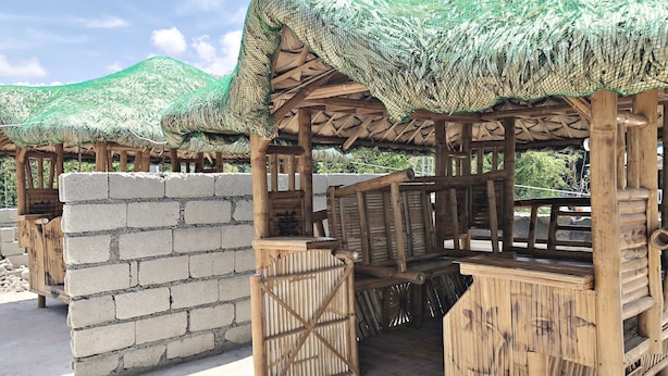 A wooden structure with a thatched roof, a brick wall, and a wooden bench.