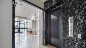 Een moderne lift met een marmeren afwerking en een digitaal scherm.