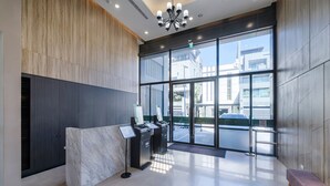 Een moderne lobby met een marmeren receptiebalie, glazen deuren naar buiten en een bank.