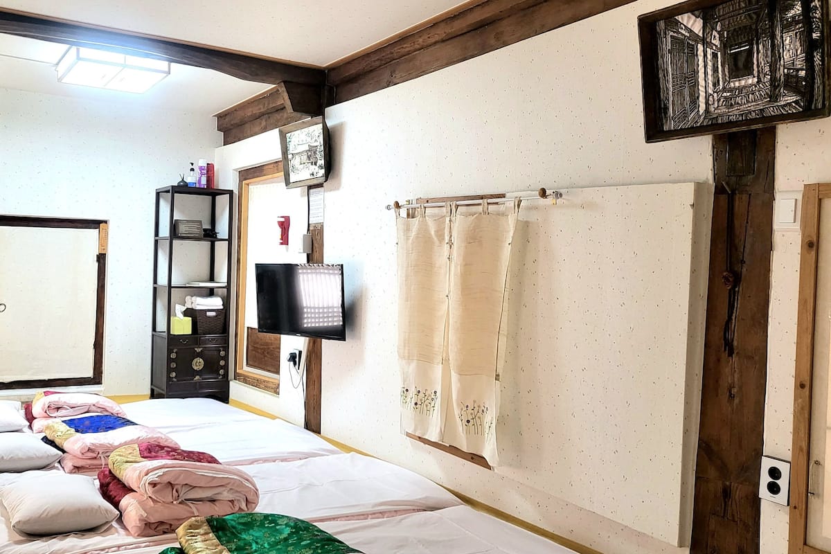 A room with a bed, a television, a shelf with toiletries, and a door.