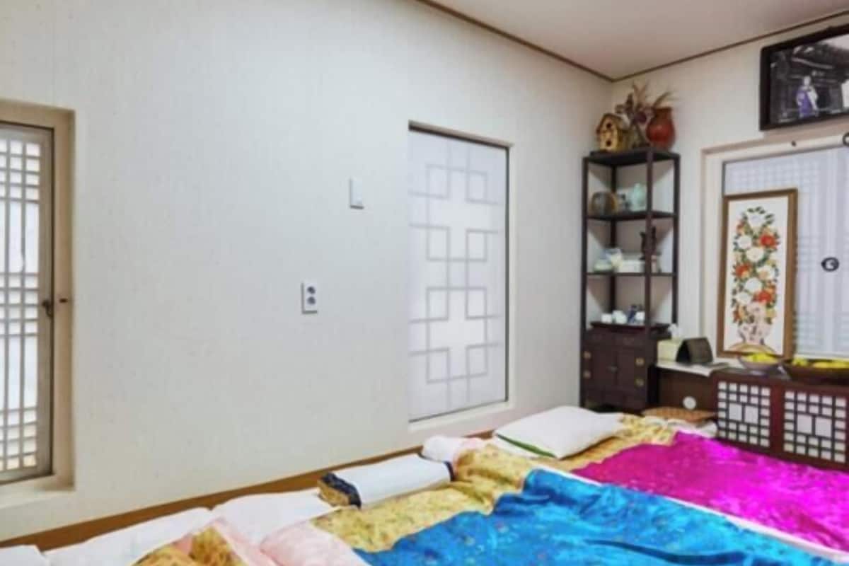 A bedroom with a bed, a wardrobe, a shelf with decorative items, and a door.