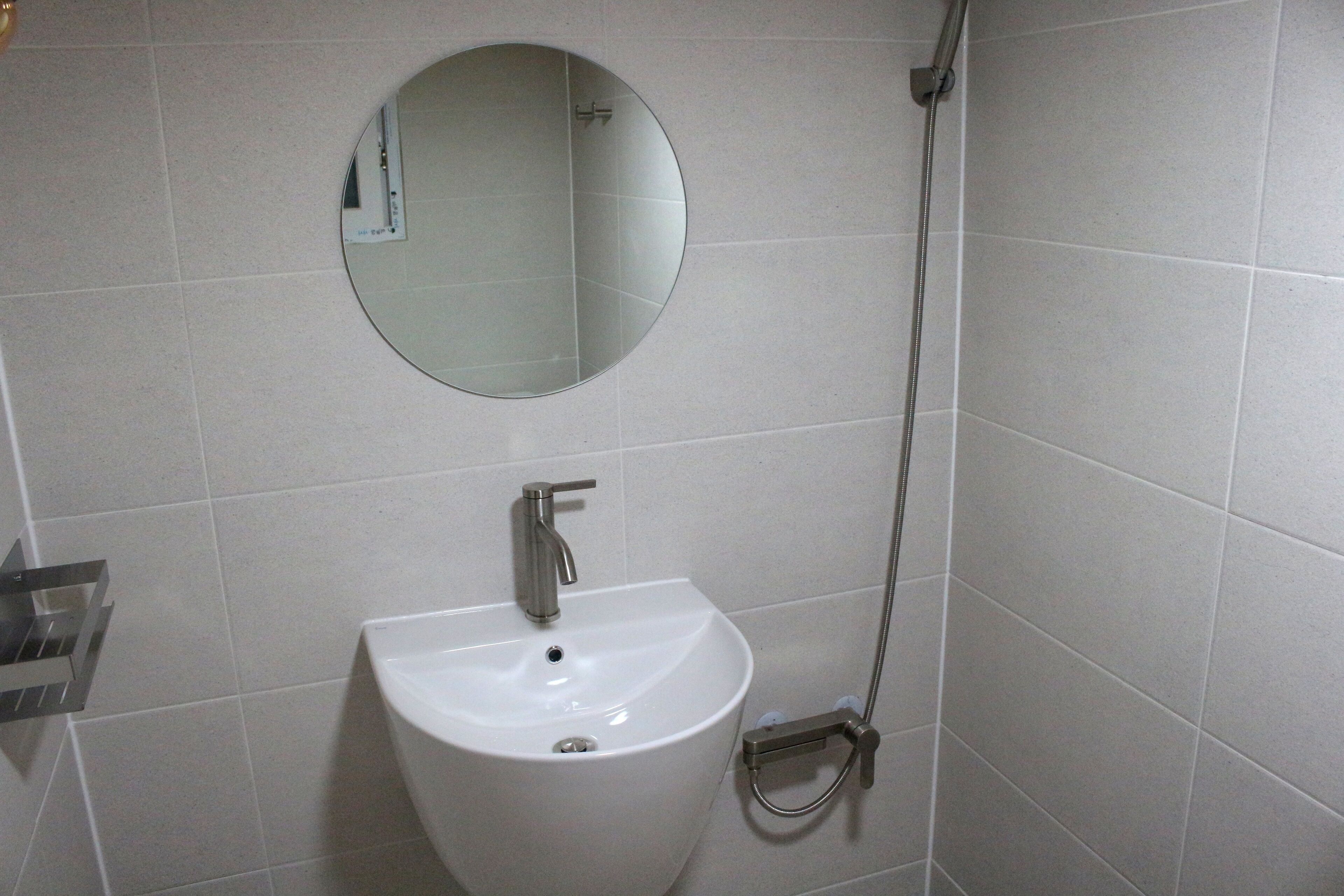 A bathroom with a white sink, a round mirror, and a shower.