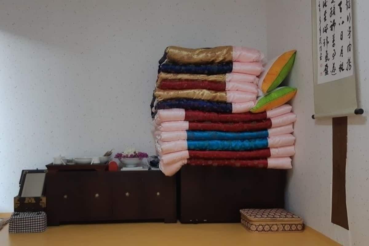A room with a bed, a small table, and a wall-mounted shelf.