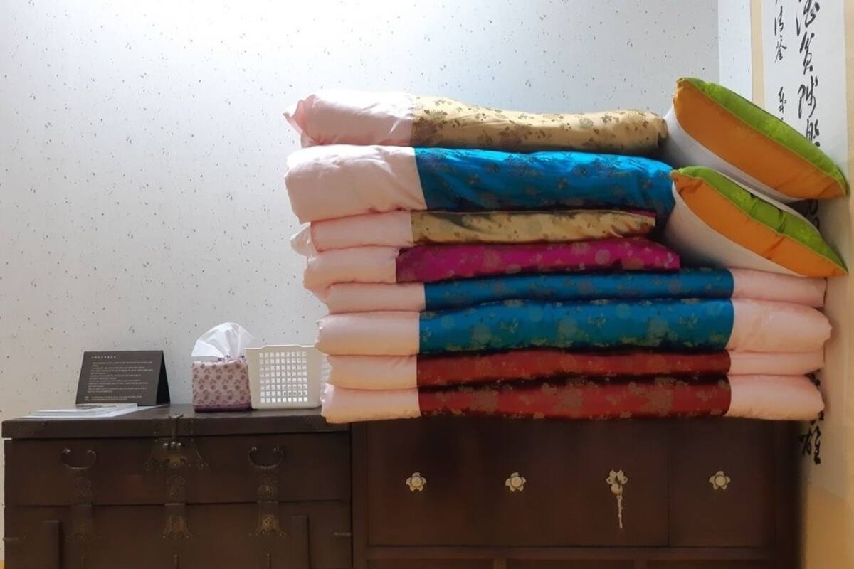 A stack of colorful towels on a dresser with a tissue box and a sign.