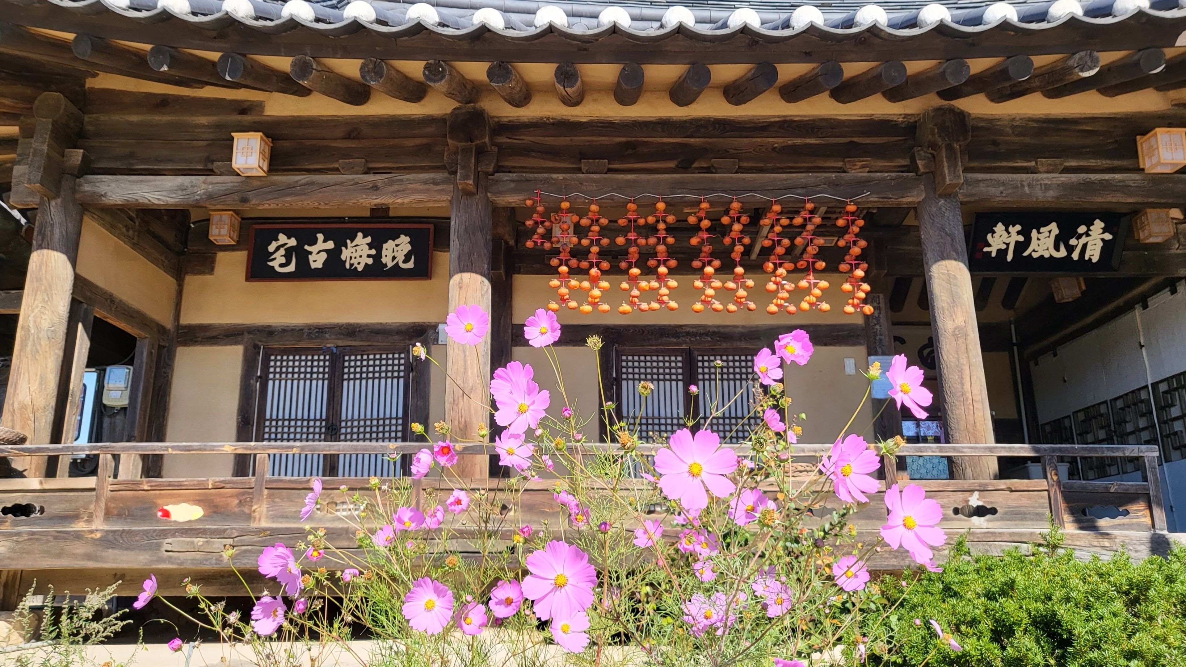 A traditional wooden building with a tiled roof, wooden beams, and a signboard.
