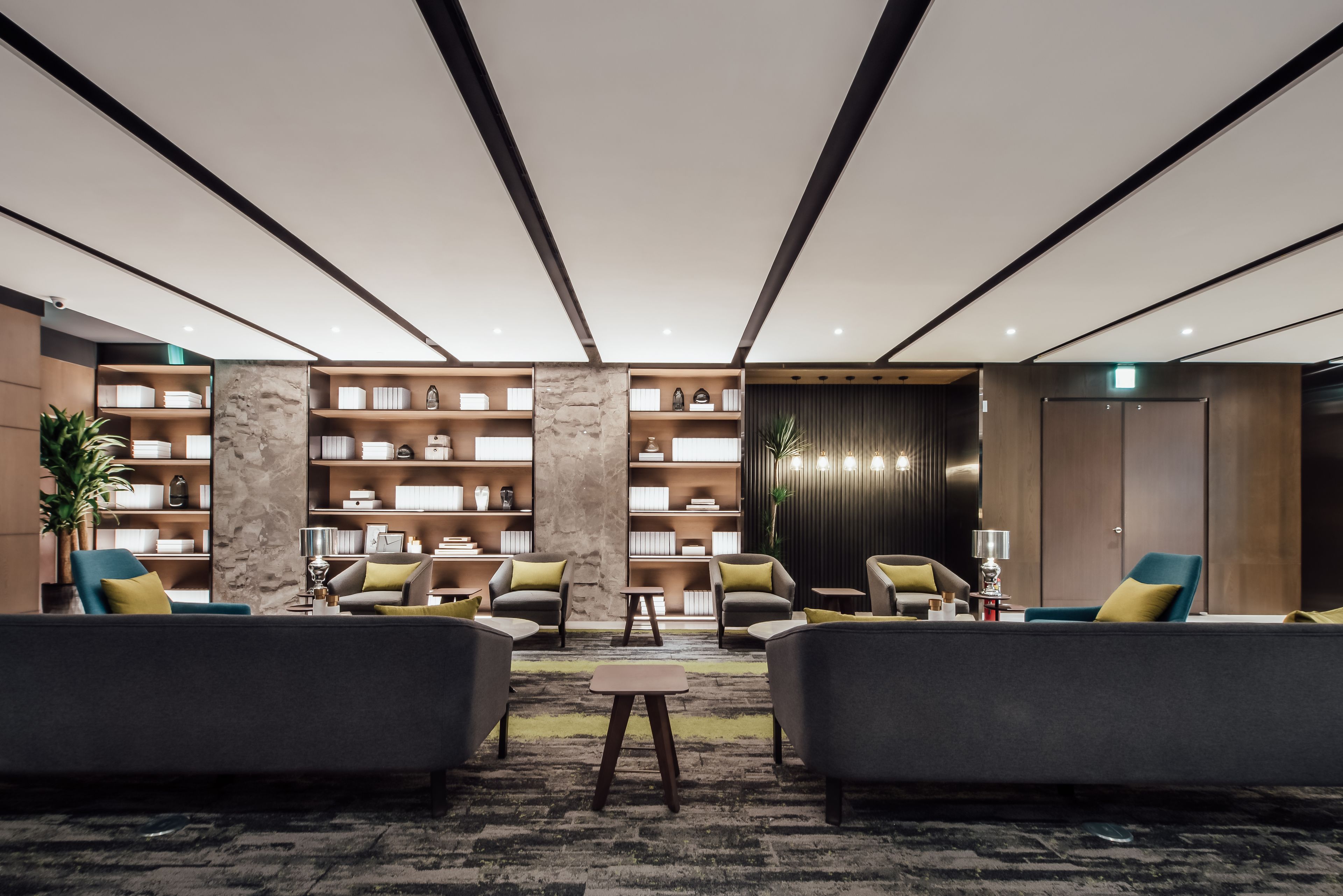 A modern lobby with sofas, a coffee table, and bookshelves.