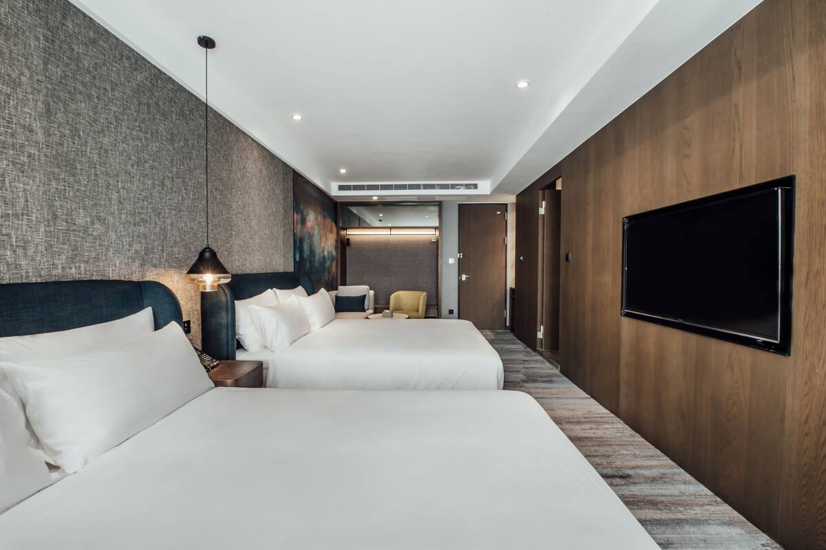 Habitación de hotel con dos camas, televisión, escritorio y una silla.