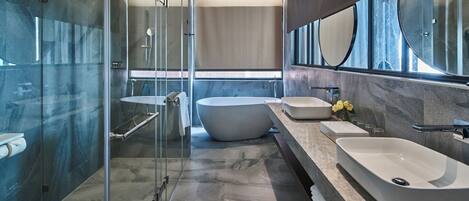 A modern bathroom with a glass-enclosed shower, a freestanding bathtub, and a large vanity with two sinks.