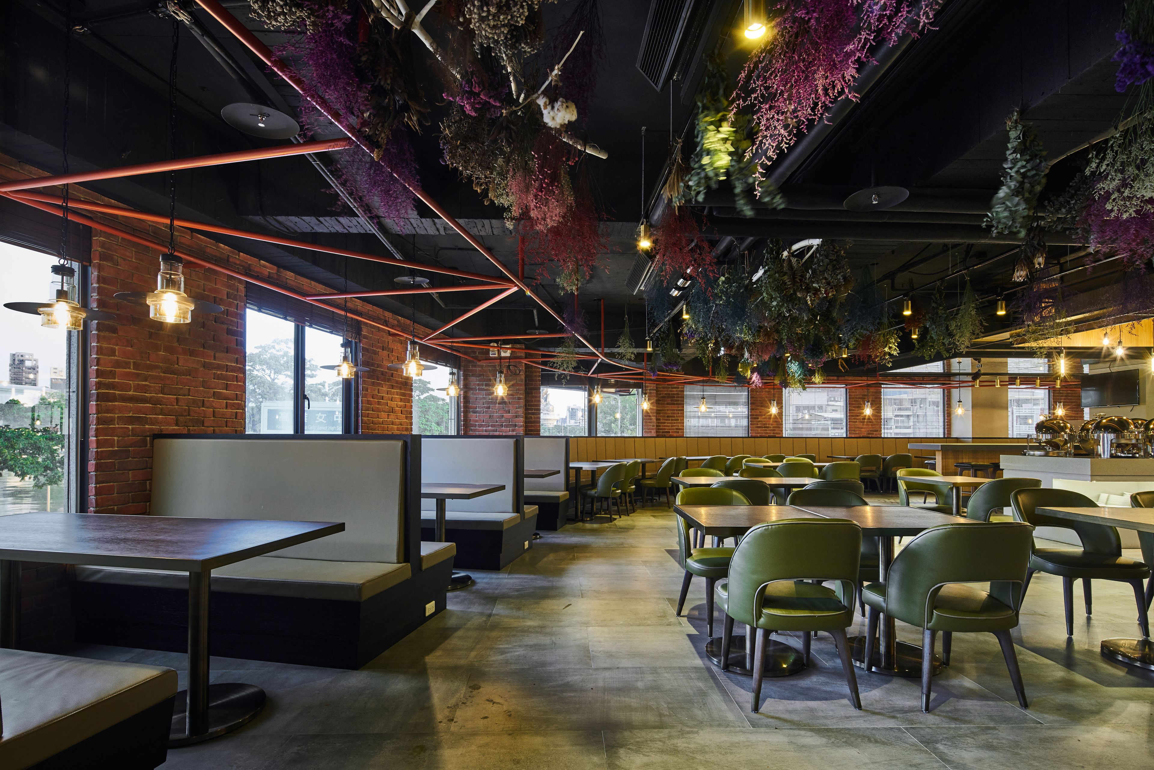 A restaurant with high tables and booths, green chairs, and hanging plants.