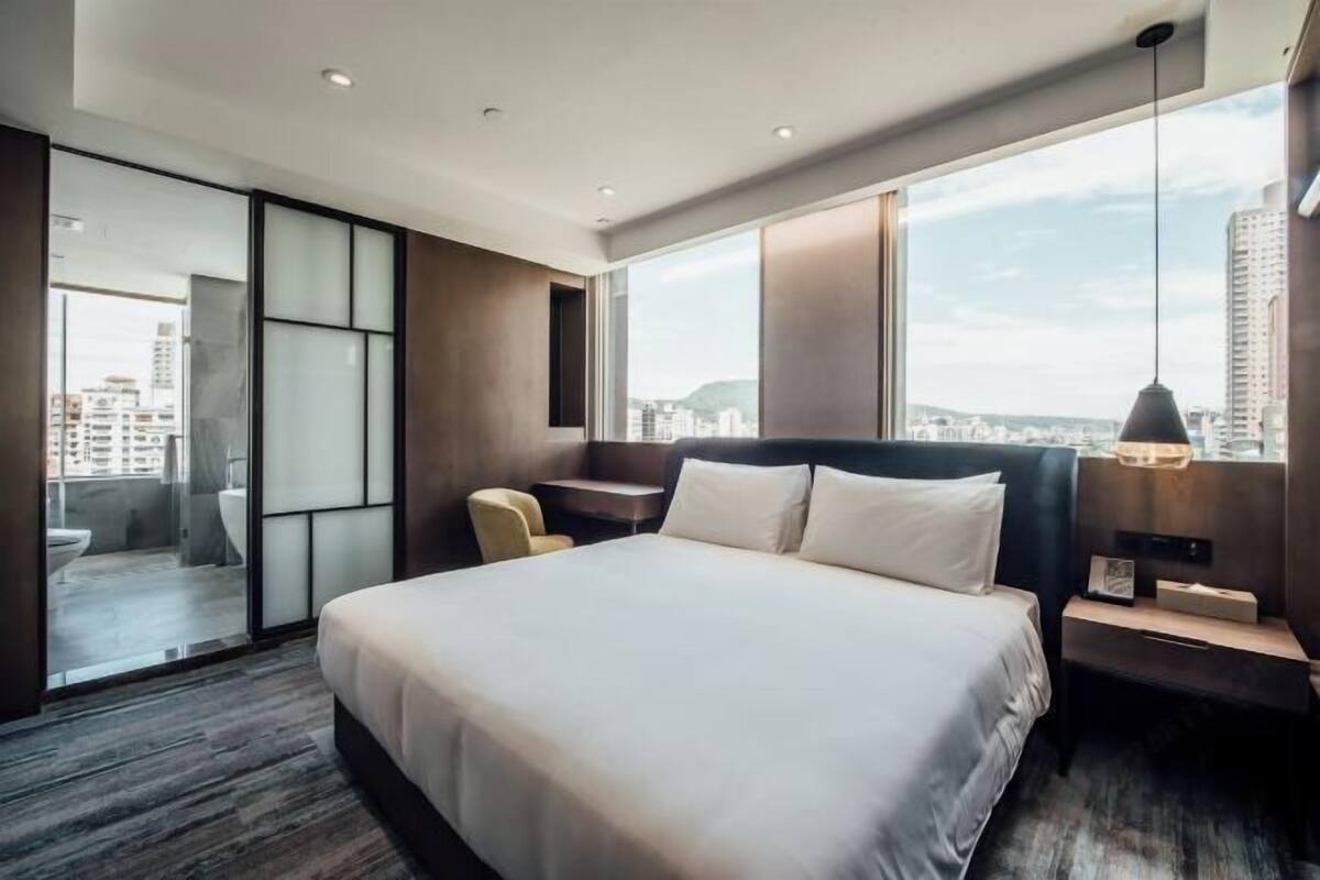 Un hotel moderno con una cama grande, un escritorio, una silla y vistas a la ciudad.