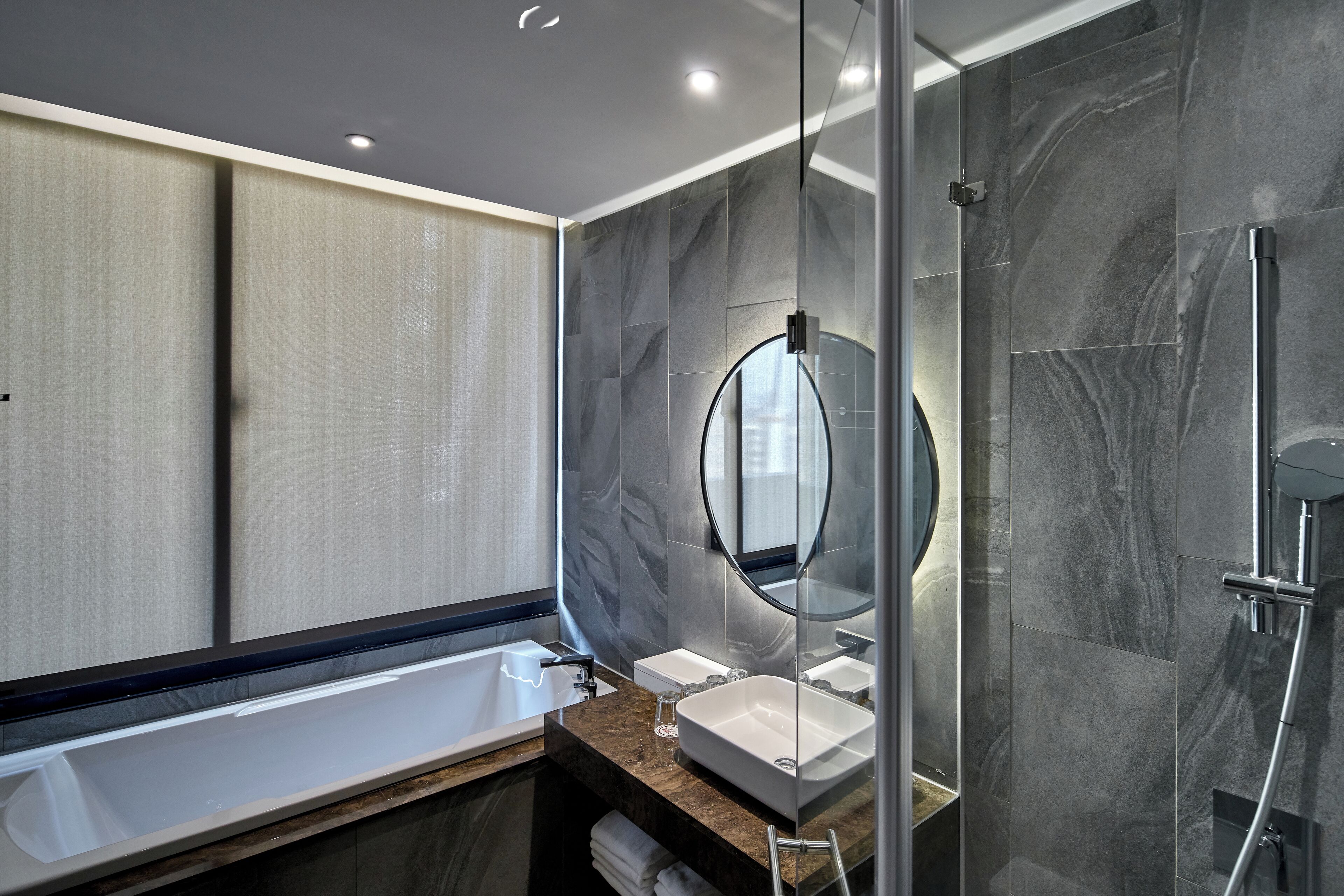 Un baño moderno con una bañera grande, una ducha con mampara de vidrio y un tocador con espejo.