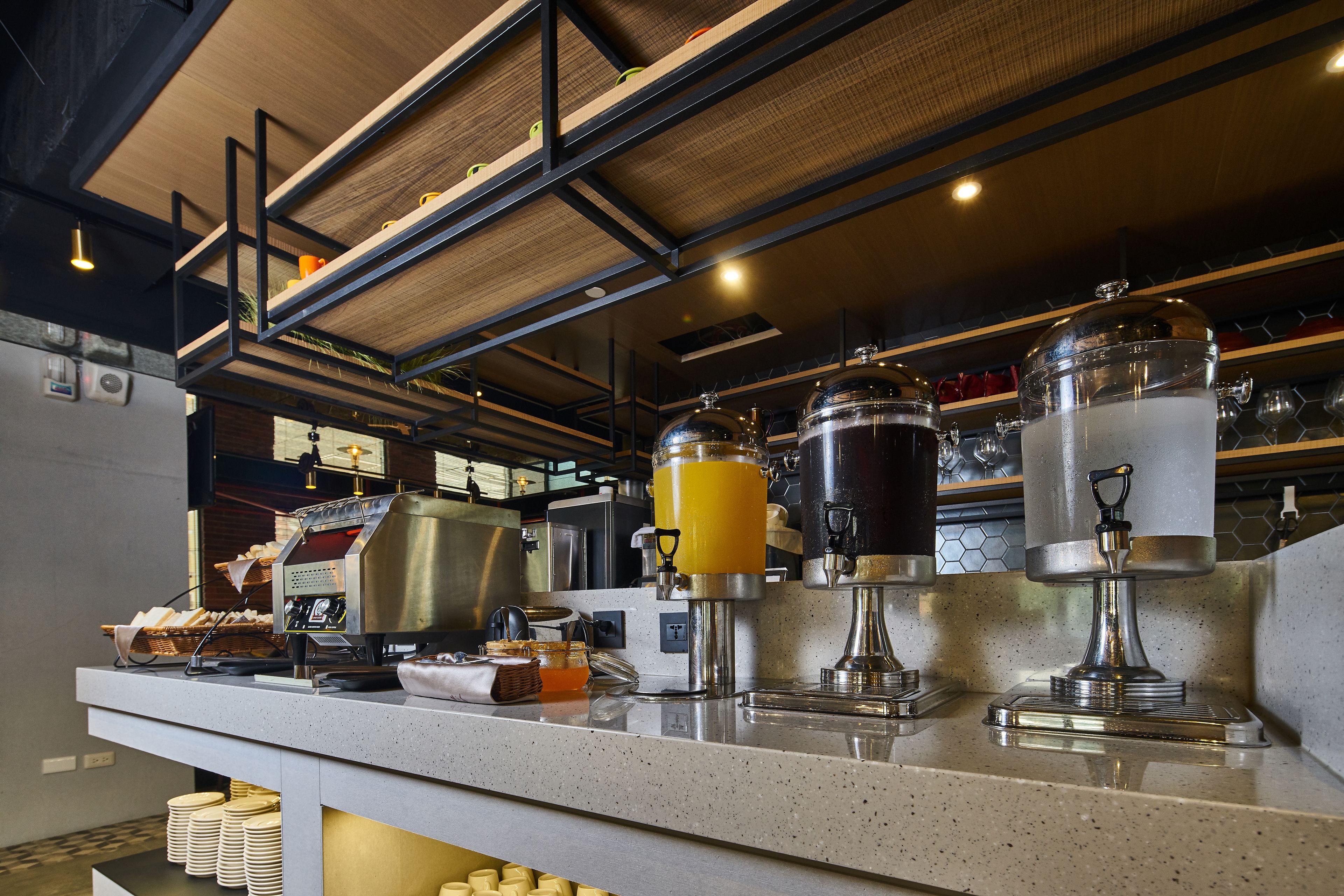 Ein Frühstücksbuffet mit Kaffeeautomaten, Saftspendern und einer Stapel Teller.