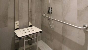 A modern bathroom with a walk-in shower, a grab bar, and a bench.