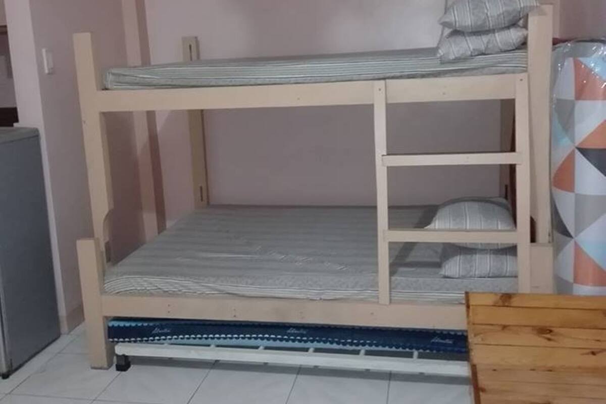 Habitación con literas, una mesita pequeña y un aire acondicionado en la pared.
