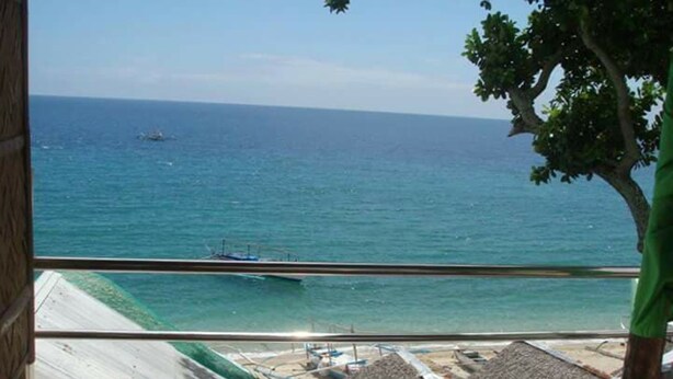 A view from a balcony overlooking a beach with a boat in the water and construction in the foreground. - Antipolo Beach Haus Annex (San Juan)