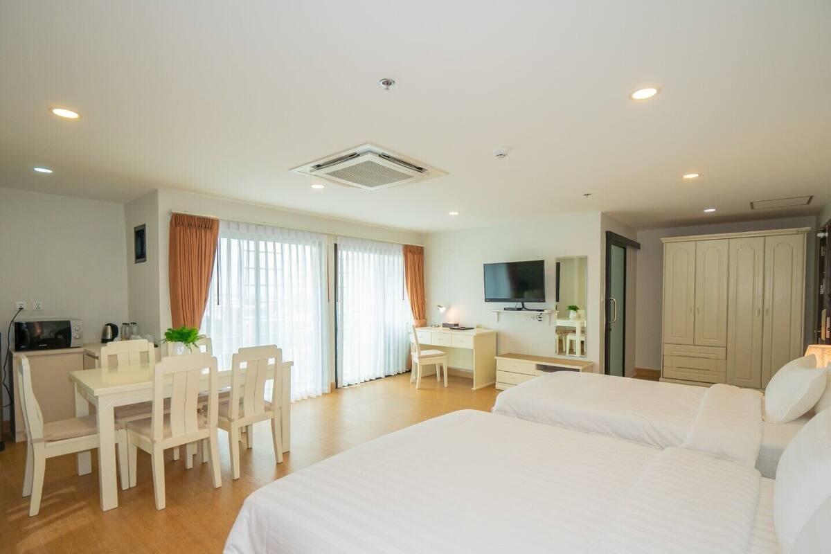 A hotel room with two beds, a desk, a chair, a television, and a wardrobe.