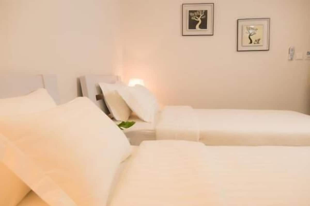 A hotel room with two beds, white bedding, a nightstand with a lamp, and two framed pictures on the wall.
