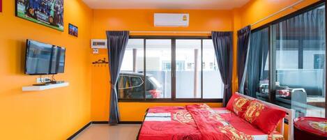 A hotel room with a bed, a television, a window with curtains, and a ceiling with a light fixture.