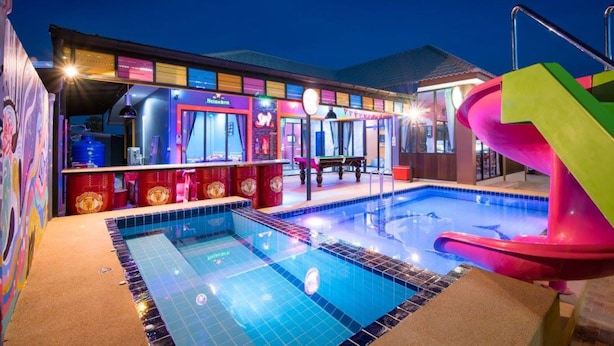 Una piscina con tobogán, zona de bar y solárium junto a la piscina.