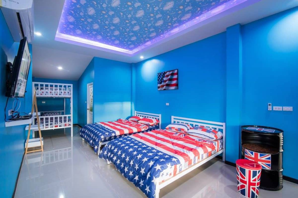A room with two beds, a bunk bed, a ceiling with a star pattern, and an American flag on the wall.