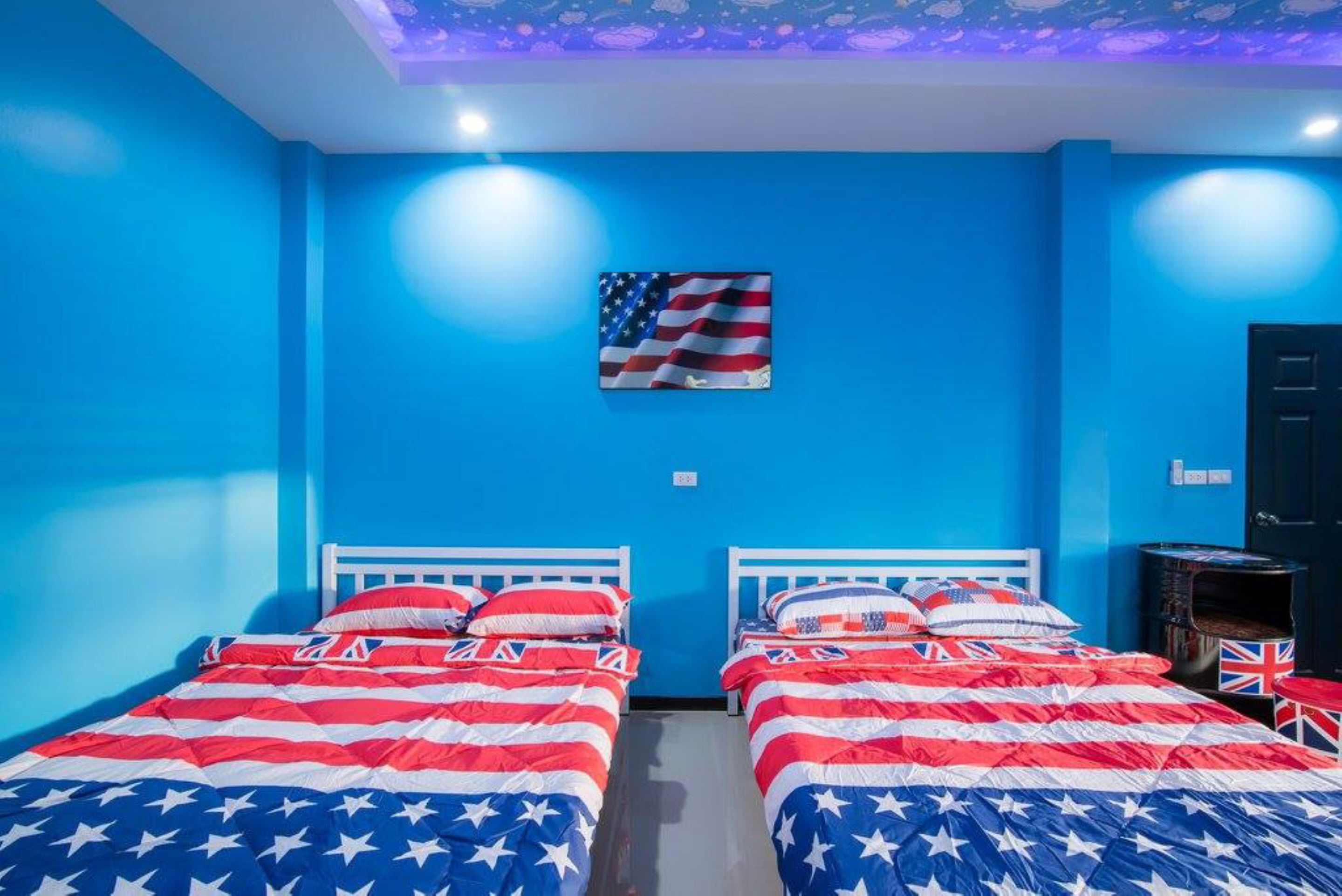 Une chambre avec deux lits, chaque lit étant placé devant un mur bleu et sous un plafond orné d’un motif étoilé.