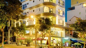 Un hôtel à plusieurs étages doté de balcons, d’une entrée bien visible et d’espaces extérieurs aménagés pour s’asseoir.