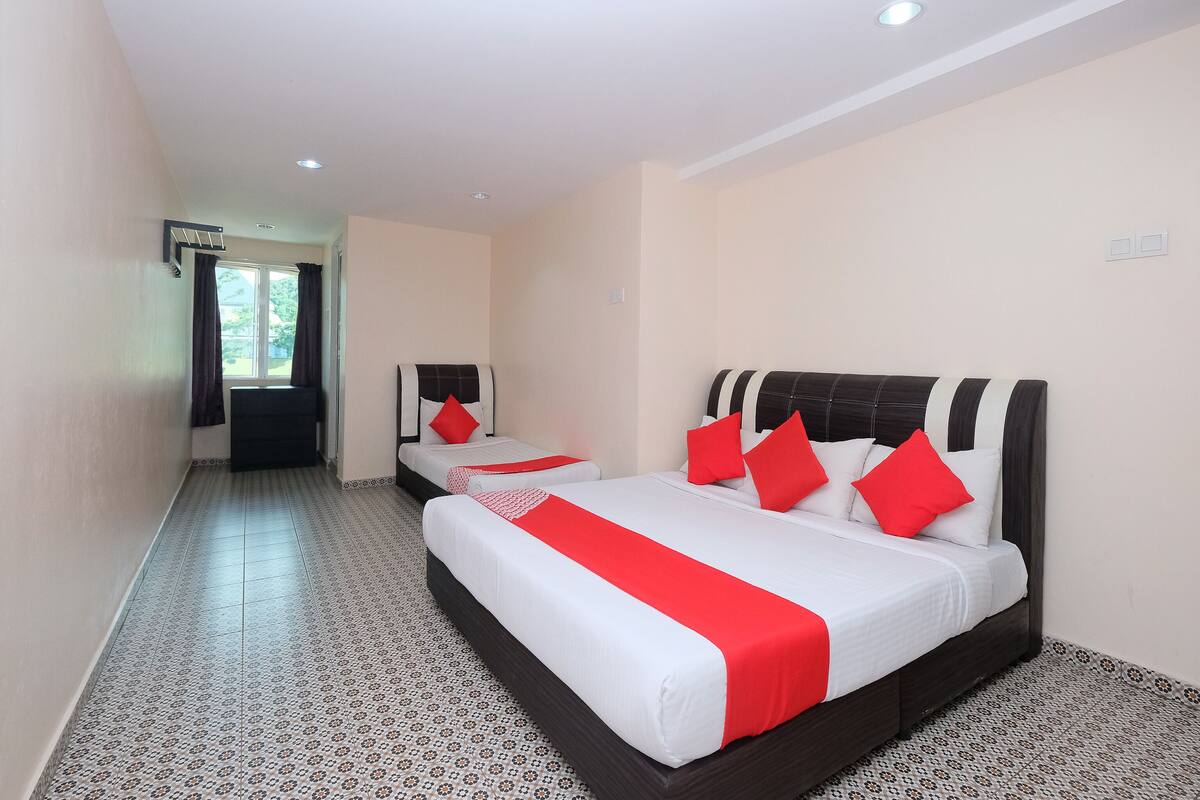 A hotel room with two beds, each with a red and white bedspread, and a patterned floor.