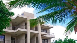A multi-story building with balconies, a swimming pool, and surrounding greenery. - Residence Theresa  Mon Choisy Mauritius (Mont Choisy)