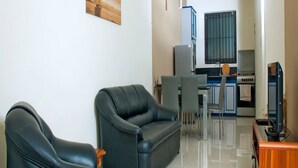 A modern living room with two black leather sofas, a dining area with a table and chairs, and a kitchen with a stove and cabinets. - Residence Theresa  Mon Choisy Mauritius (Mont Choisy)