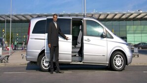 A man in a suit standing next to a silver van with its door open. - Residence Theresa  Mon Choisy Mauritius (Mont Choisy)