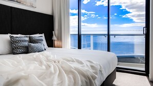 Una habitación de hotel con una cama grande, vistas al mar y un balcón.