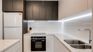 A modern kitchen with a built-in oven, a stainless steel sink, and a refrigerator.