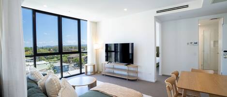 Uma sala de estar moderna com um sofá verde, uma mesa de jantar de madeira e uma TV em um móvel.