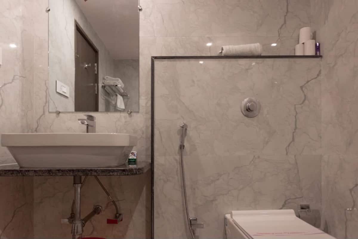 A modern bathroom with a marble sink, a glass-enclosed shower, and a toilet.