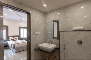 A modern bathroom with a marble sink, a mirror, and a shower. - Hari Vilaas (Varanasi)