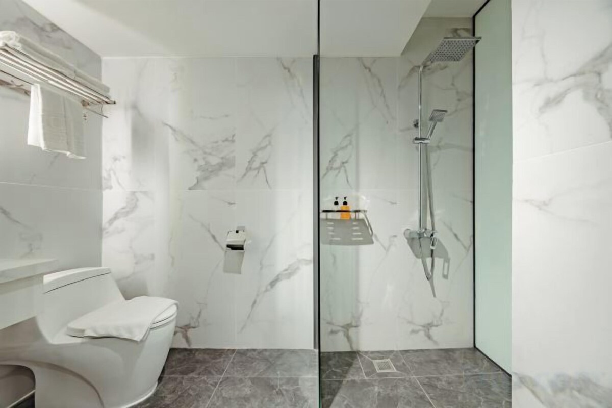 Un baño moderno con un tocador curvo, inodoro y zona de ducha con mampara de vidrio.
