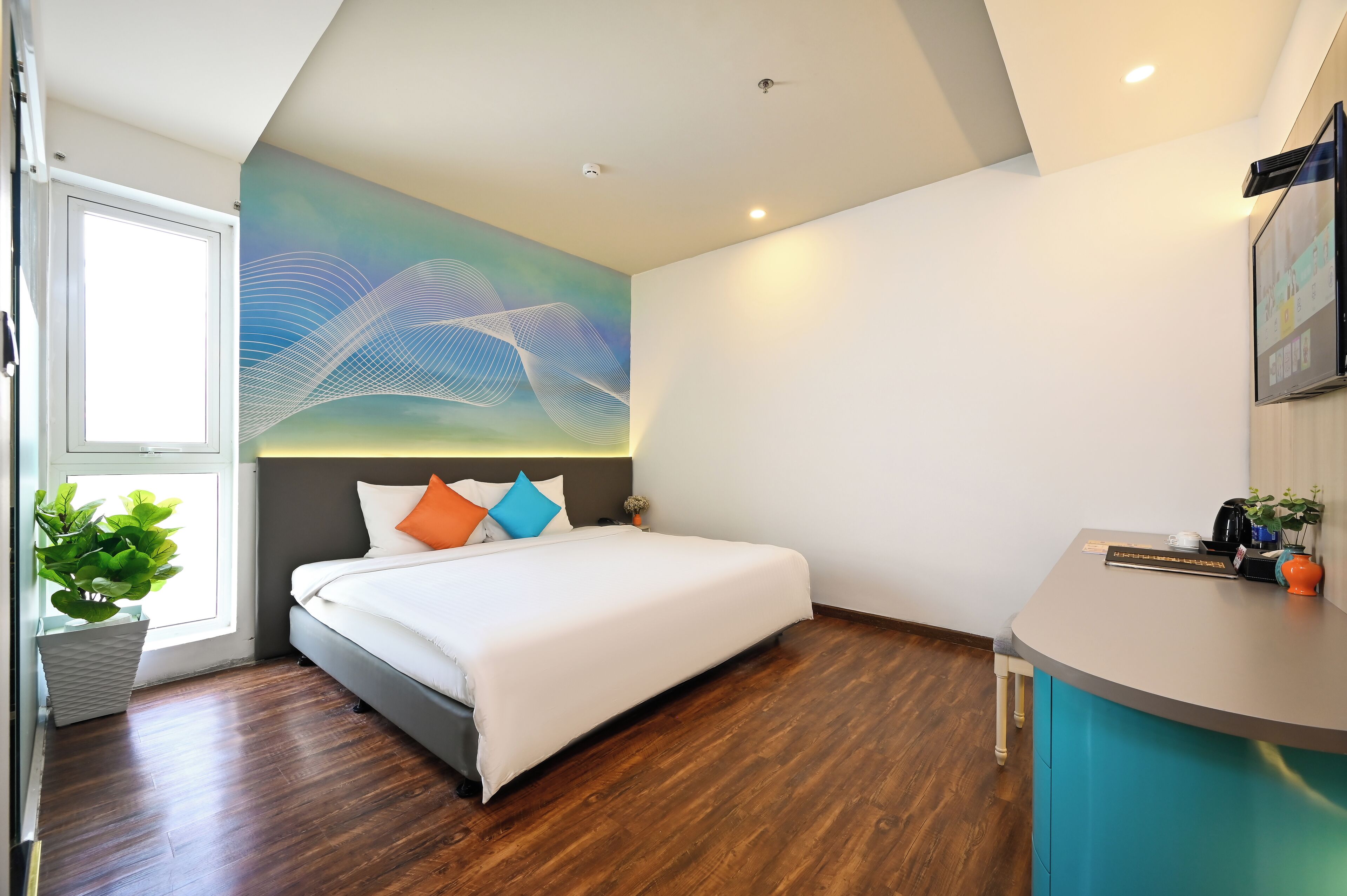 A modern hotel room with a large bed, a desk, and a wall-mounted TV.